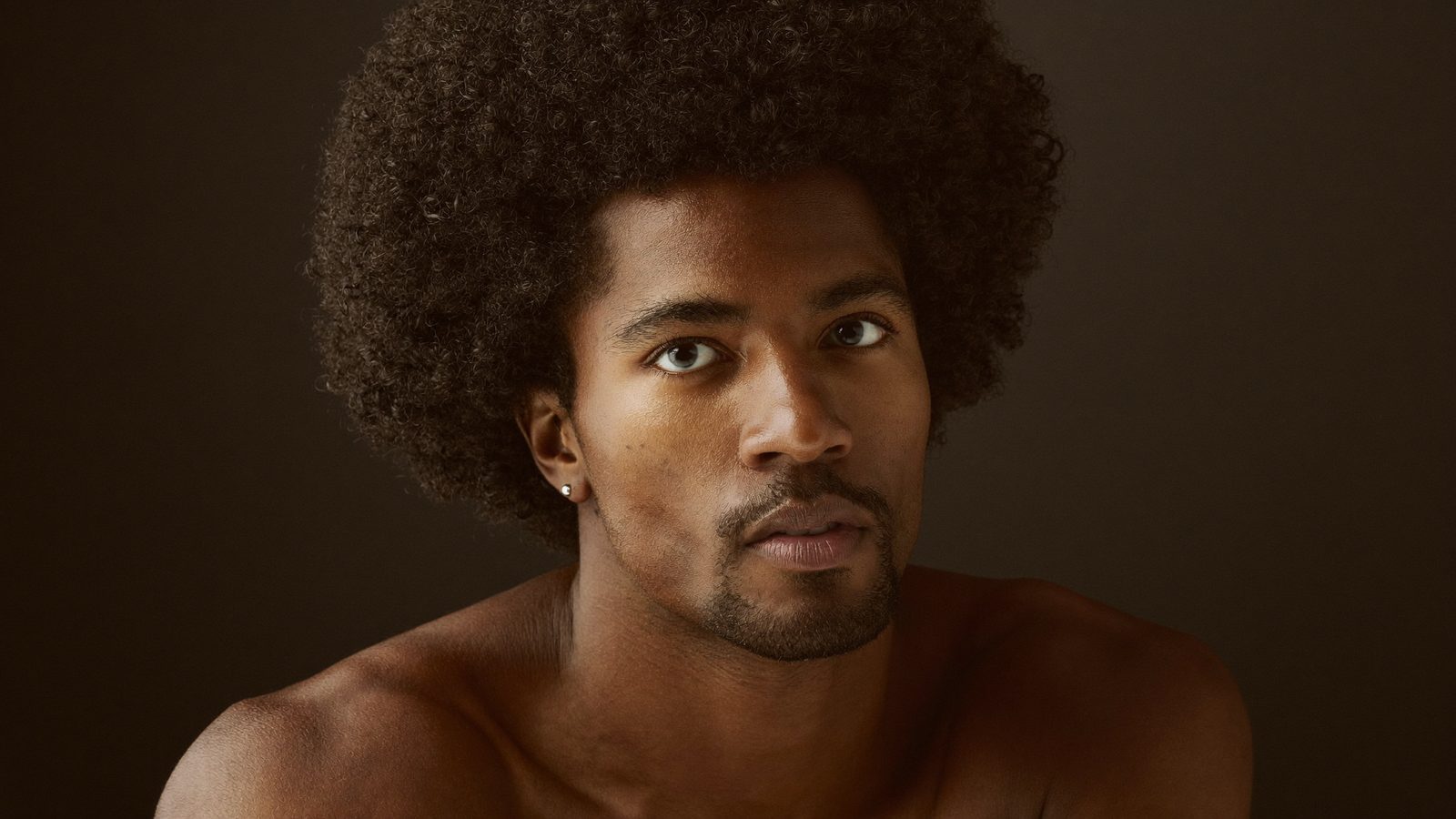 Portrait of a man with healthy, tightly curled afro hair in warm light