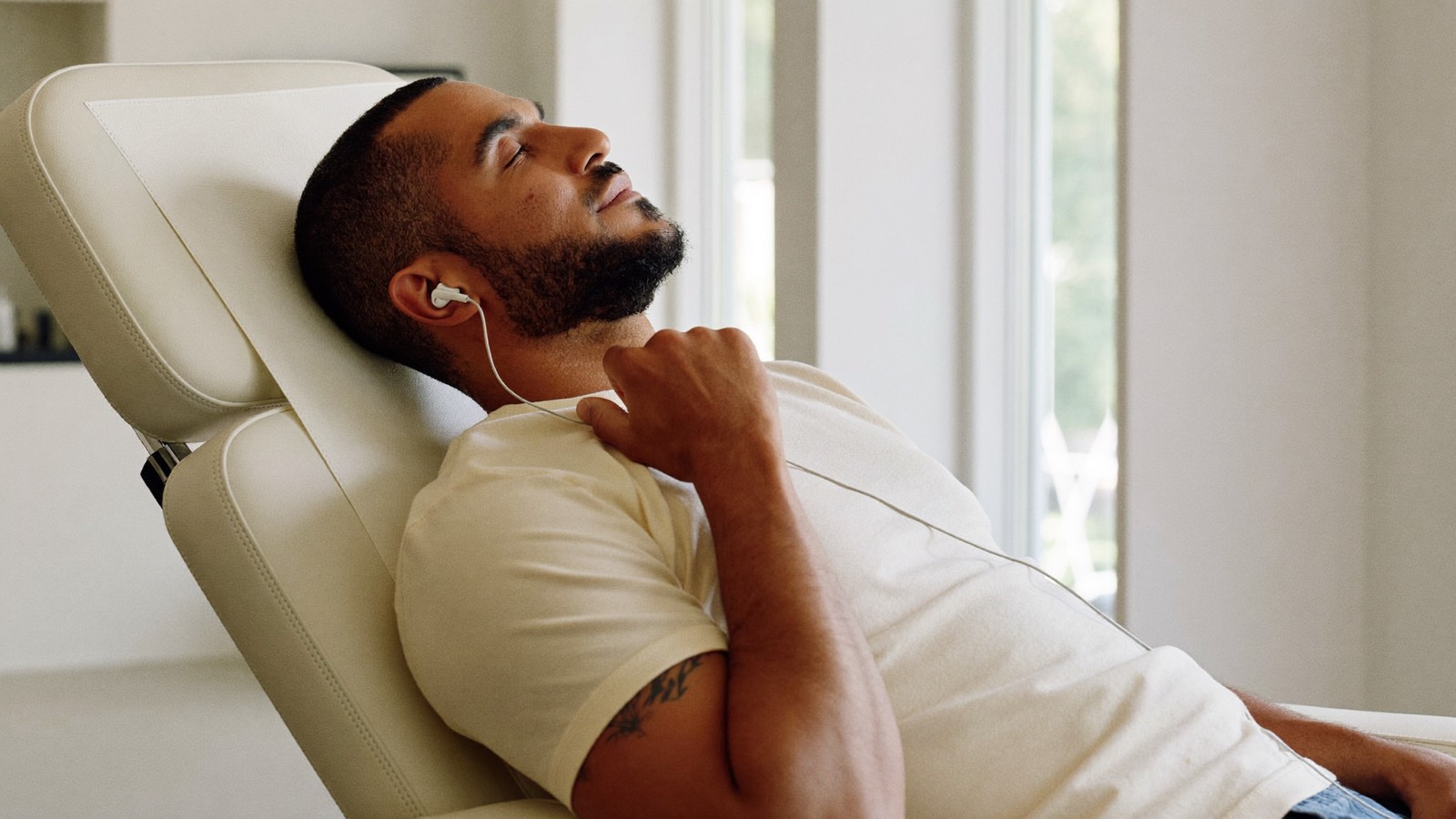 Man resting with his eyes closed in a reclining clinic chair, listening to music