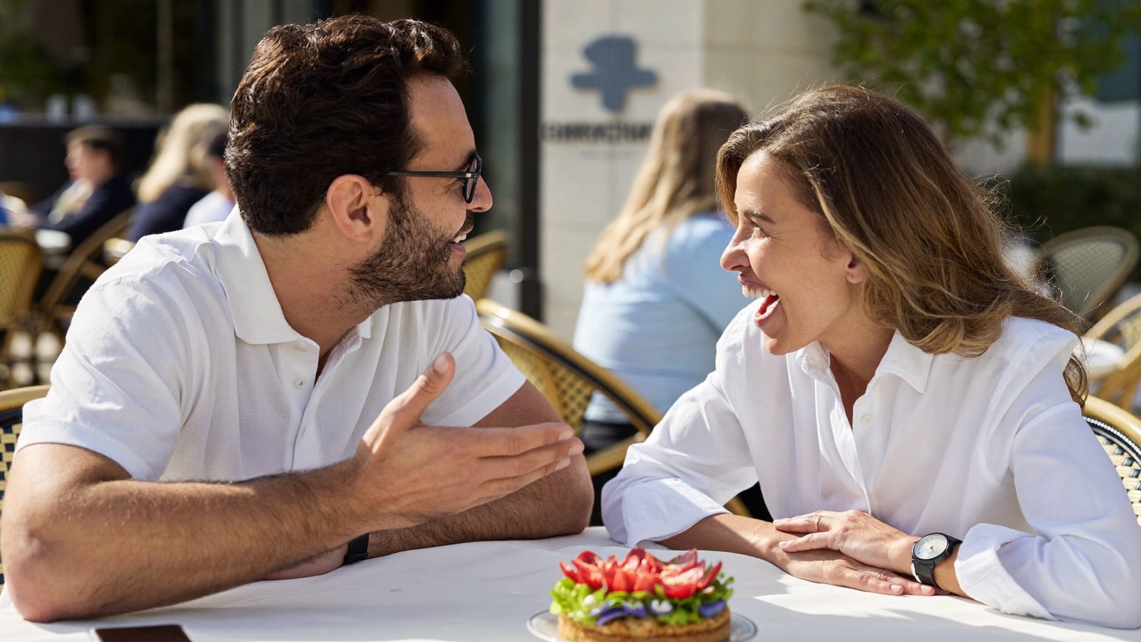 Man and woman chatting animatedly at a sunny outdoor cafe table