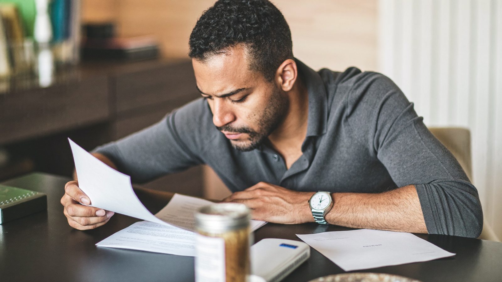 Man reviewing paperwork at a desk with a cup of coffee