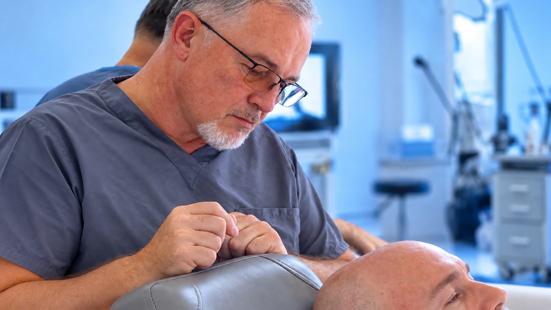 Clinician in scrubs working on a patient's scalp during a DHI hair transplant procedure